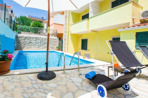 a swimming pool with an umbrella and a baby stroller at Sunrise Apartments in Cavtat