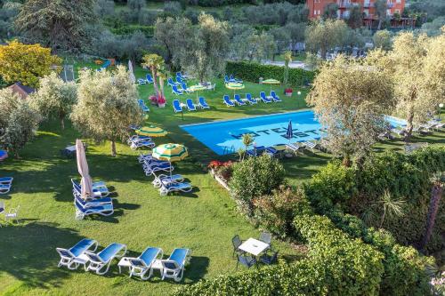 an aerial view of a lawn with chairs and a swimming pool at Hotel Astoria - 3stelle S in Malcesine