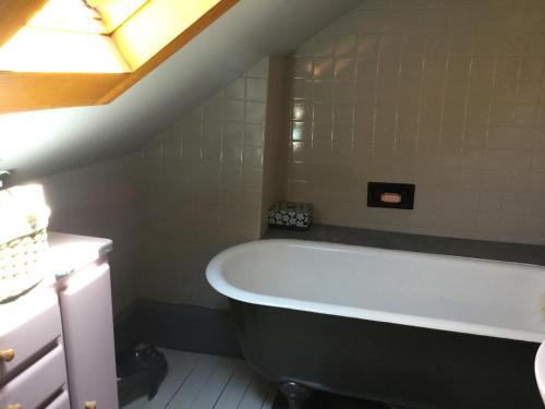 La salle de bains mansardée est pourvue d'une baignoire. dans l'établissement Charmante maison de ville avec jardin et piscine, à Auxerre