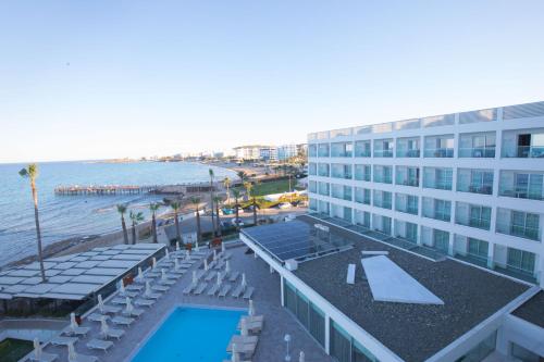 a hotel with a pool and chairs and a beach at Evalena Beach Hotel in Protaras