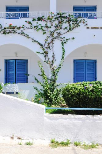 a white building with blue doors and a plant at Kalimera Studios and Apartments in Moraitika