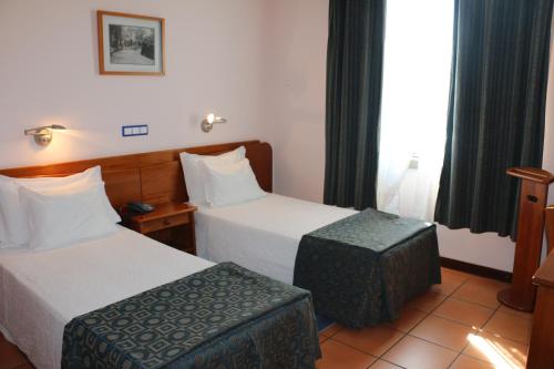 a hotel room with two beds and a stool at Apartamentos Turisticos Verdemar in Horta