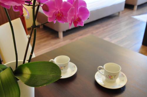 two cups and a vase with flowers on a table at Willa Ewa in Międzyzdroje