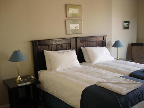 twee bedden in een kamer met twee lampen op tafels bij Cornerstone Guesthouse in Swakopmund