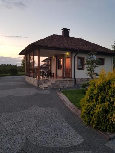 ein Haus mit einer Veranda und einer Auffahrt in der Unterkunft Vesyolaya Rochsha in Kamjanske