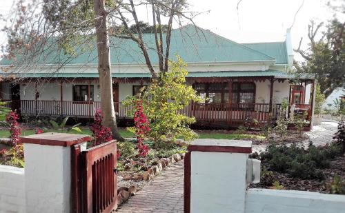 a house with a fence and flowers in front of it at Green Olive Guesthouse in Robertson