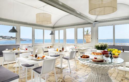 een restaurant met witte tafels en stoelen en de oceaan bij Villa delle Palme in Santa Marinella