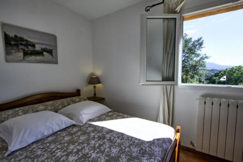 1 dormitorio con cama y ventana en A Ghjuvellina, en Piedigriggio