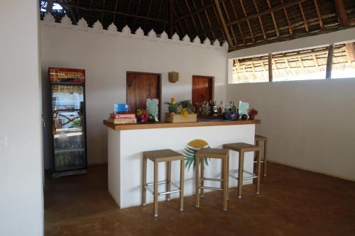 a bar in a room with stools and a refrigerator at Kiganja in Matemwe