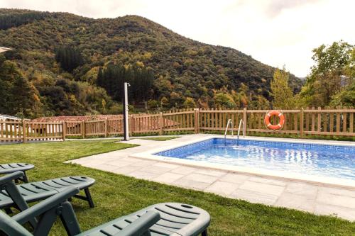 a backyard with a swimming pool with chairs and a fence at La Dobra de liebana in Cambarco