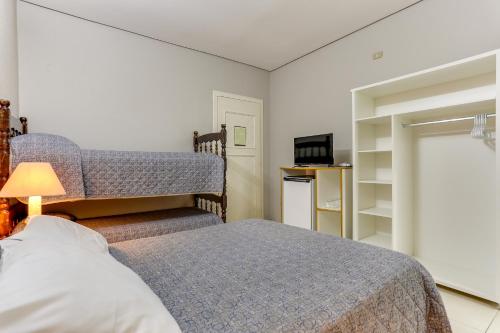 a bedroom with a bed and a lamp and a television at Canasvieiras Hotel in Florianópolis