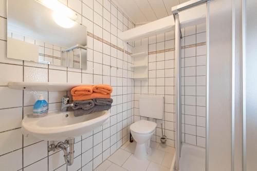 ノルダーナイにあるHaus Albatros App. Storchennestの白いタイル張りのバスルーム(トイレ、シンク付)