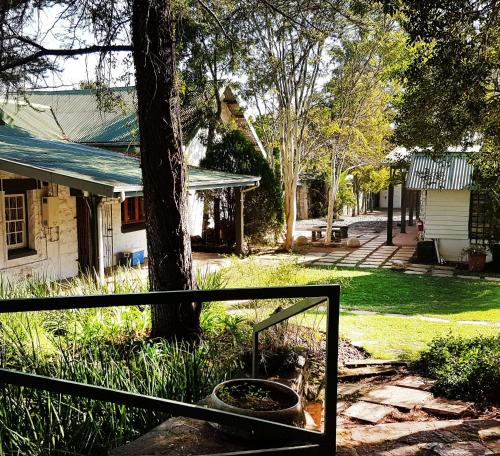 a fence in front of a house with a tree at Farquhar Lodge in Ladysmith