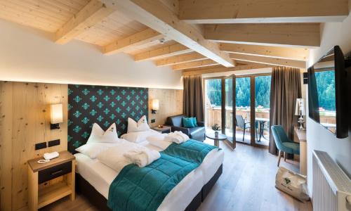 a bedroom with a large bed and a room withwindows at Wellness Hotel Gran Risa***S in La Villa
