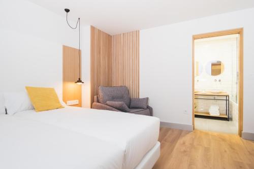 a bedroom with a white bed and a chair at Pensión Arroka in San Sebastián