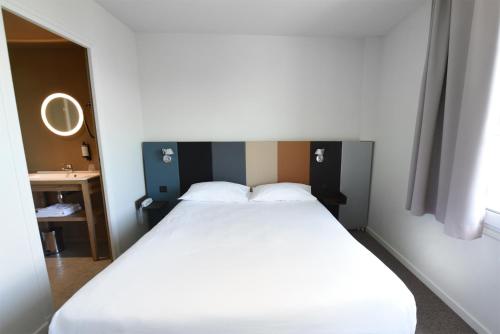 a bedroom with a large white bed in a room at Cit'Hotel De Harlay in Compiègne