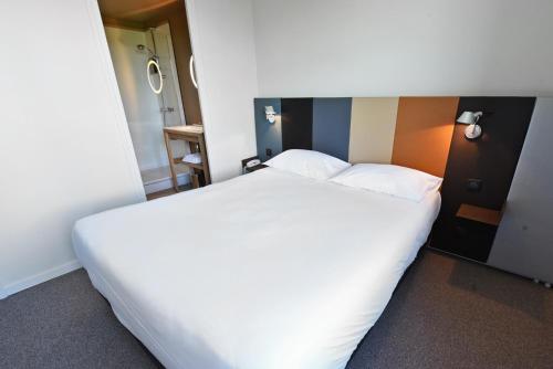 a large white bed in a hotel room at Cit'Hotel De Harlay in Compiègne