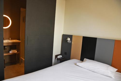 a bedroom with a white bed and a bathroom at Cit'Hotel De Harlay in Compiègne