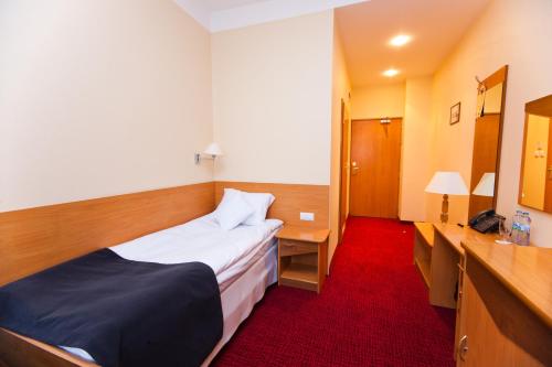 a small hotel room with a bed and a desk at Hotel Malinowski Business in Gliwice