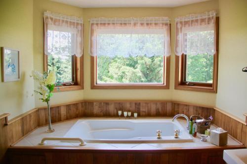 uma banheira na casa de banho com 2 janelas em A Touch of Country B&B em Stratford