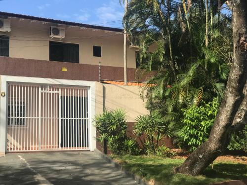 a house with a gate and a palm tree at Suite Cardoso in Foz do Iguaçu