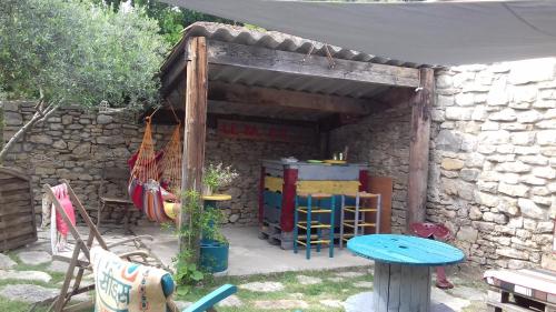 a stone shelter with a table and chairs in a yard at Un nid entre vignes et pierres "Pic St Loup" Claret in Claret