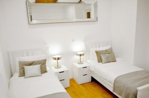 a bedroom with two beds and a mirror on the wall at Intendente Terrace in Lisbon