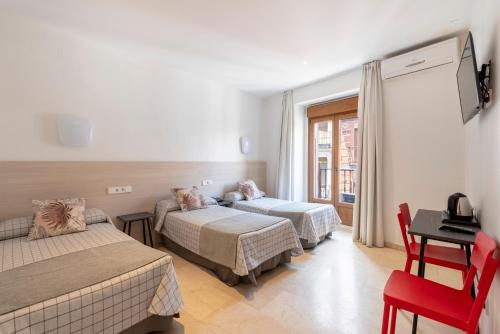 a hotel room with two beds and a table and chair at Hostal Castilla II Puerta del Sol in Madrid