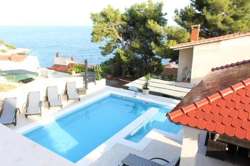 a swimming pool with chairs and the ocean in the background at Villa Omazic in Trogir