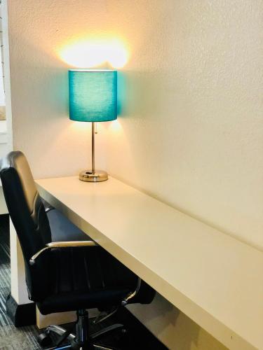 a desk with a lamp and a chair at BridgePoint Inn Daly City in Daly City