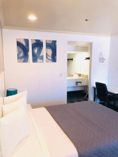 a bedroom with a bed and a desk and a table at BridgePoint Inn Daly City in Daly City