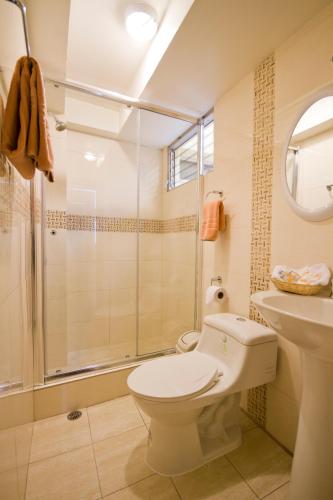 a bathroom with a shower and a toilet and a sink at Hotel Sandmelis in Quito
