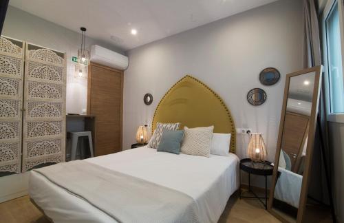 Un dormitorio con una gran cama blanca y un espejo. en AbraCadabra Suites, en Madrid