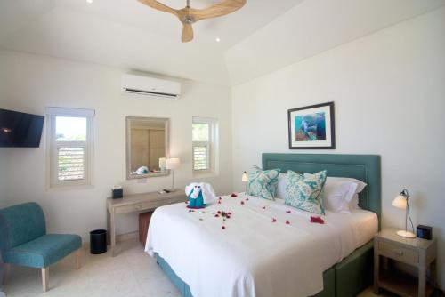 a bedroom with a large bed and a blue chair at The Liming Bequia in Friendship
