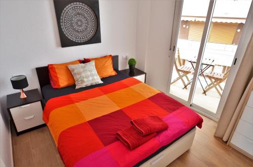 アリカンテにあるLuxury beachside apartmentのバルコニー付きの客室のカラフルなベッド1台分です。
