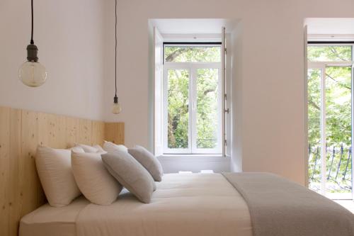 een witte slaapkamer met een groot bed met witte kussens bij Destino Lisboa Apartments in Lissabon