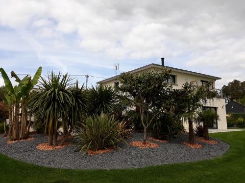 a garden in front of a house with palm trees at Chambre d'hôtes Les Bruyères in Bruc-sur-Aff