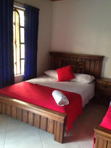 a bedroom with a bed with red and white pillows at Hotel campestre la Maria in Villavicencio
