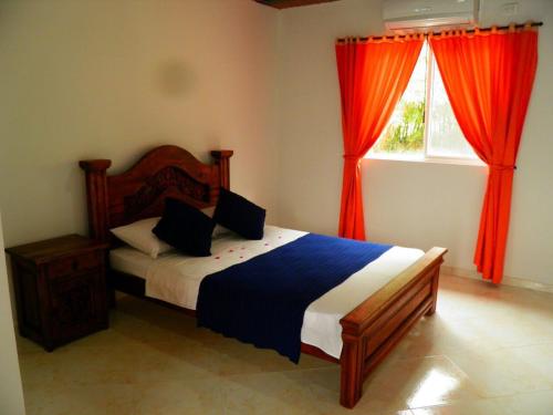 a bedroom with a bed and a window with red curtains at Hotel campestre la Maria in Villavicencio