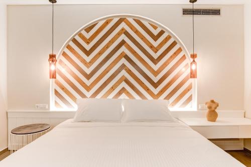 a bedroom with a white bed with a wooden headboard at Anemolia Parga Suites in Sarakiniko