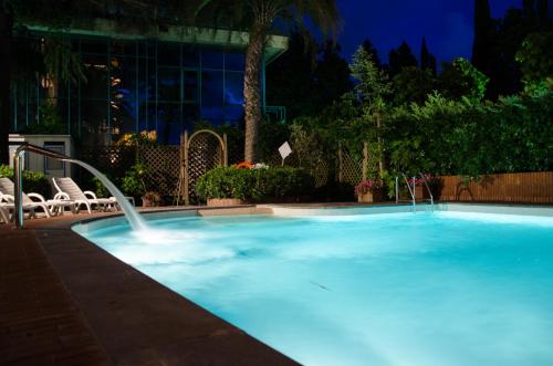 a large blue swimming pool with a water fountain at Grand Hotel Tamerici & Principe in Montecatini Terme