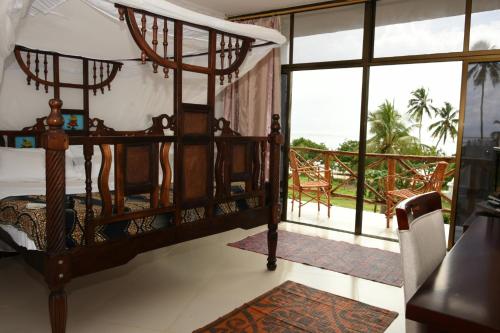 um quarto com uma cama e uma varanda em Coconut Tree Village Beach Resort em Uroa