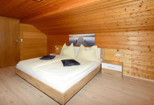 a bedroom with a large white bed in a wooden wall at Bauernhof Madlener Claudia in Schoppernau