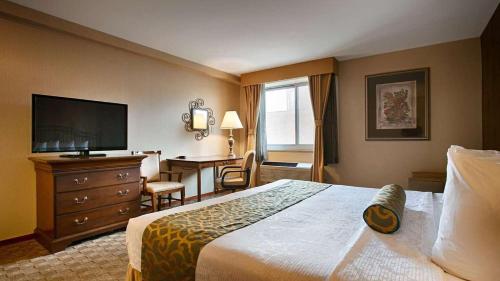 a hotel room with a bed and a desk at Best Western Queens Court in Queens