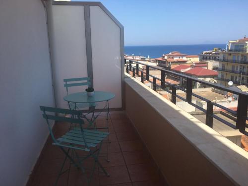a table and chairs on a balcony with a view of the ocean at Blue Sky Apartments in Capo dʼOrlando