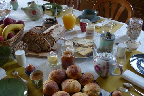 Una mesa con un desayuno de pan, frutas y huevos. en Le Clos des Fayettes, en Theizé