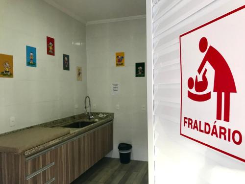 a bathroom with a sink and a sign on the wall at Cavalinho Branco Apartamento in Águas de Lindoia