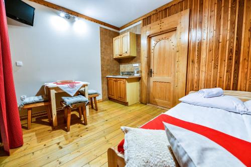 a bedroom with a bed and a table and a kitchen at Pokoje Gościnne Makuszyńskiego in Zakopane