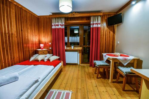 Schlafzimmer mit einem Bett, einem Tisch und einem TV in der Unterkunft Pokoje Gościnne Makuszyńskiego in Zakopane