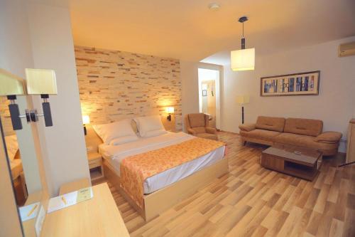 ein Schlafzimmer mit einem Bett, einem Stuhl und einem Sofa in der Unterkunft Hotel Pinocchio in Pristina
